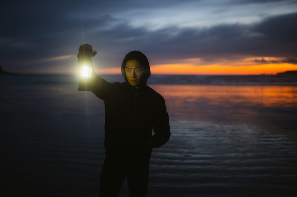 a person standing on a beach holding a light